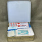 Open first aid kit with various supplies on a gray background