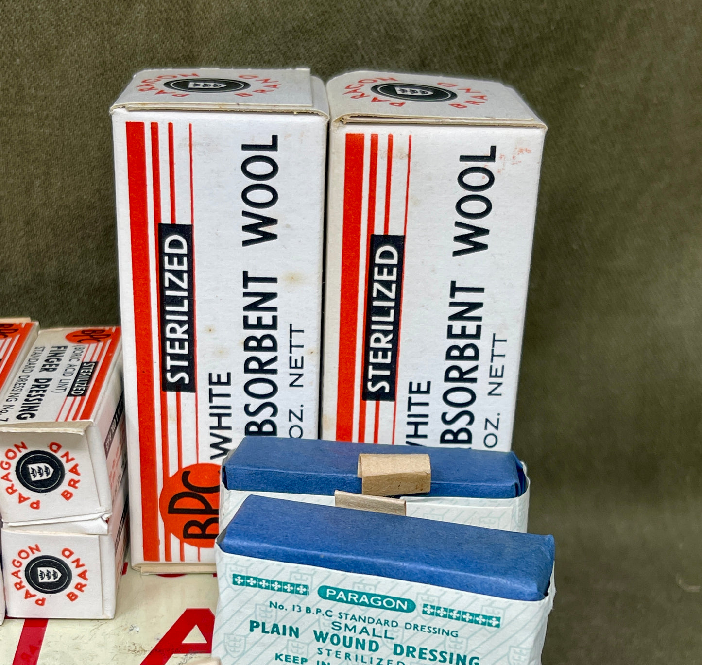 Boxes of sterilized white absorbent wool and Paragon plain wound dressing on a green background